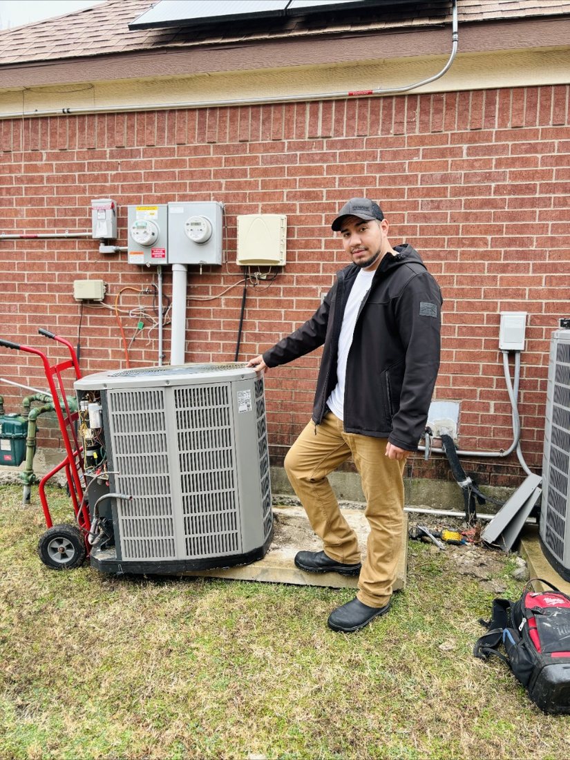 An ATC Heating and Air technician beside a residential condenser